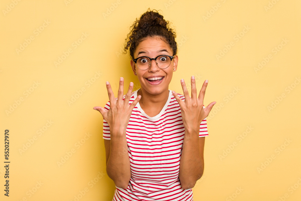 Young Brazilian curly hair cute woman isolated on yellow background showing number ten with hands. Young Brazilian curly hair cute woman isolated on yellow background showing number ten with hands.