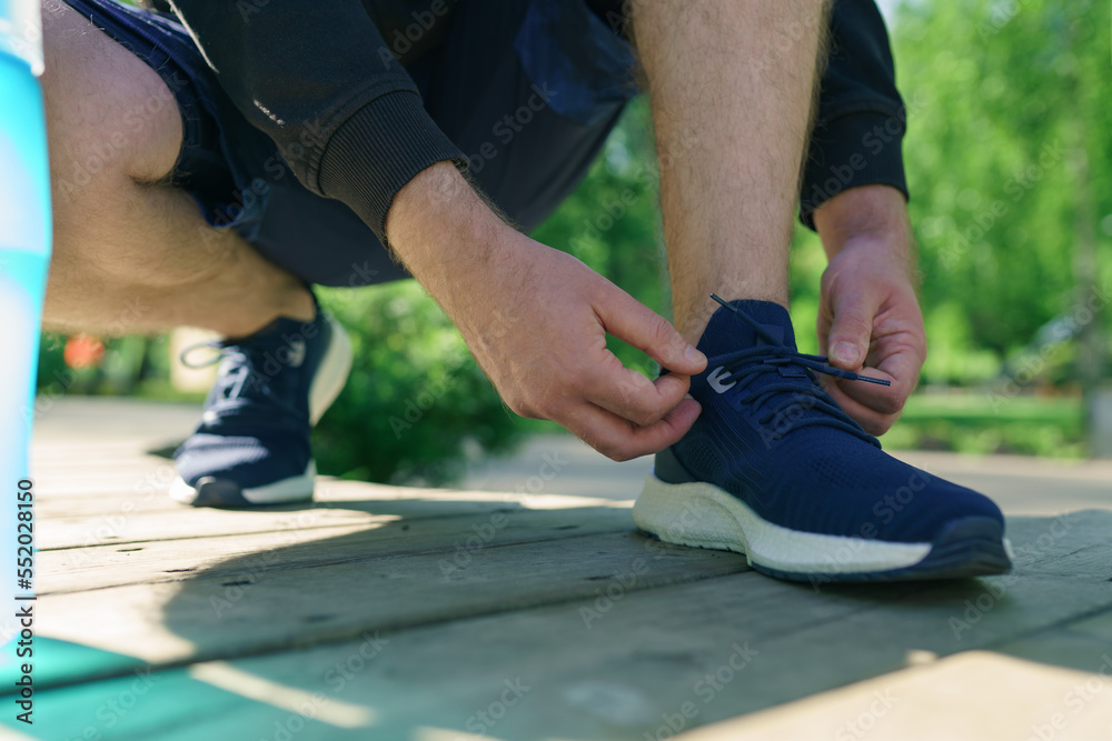 Tying sports shoes, man prepare for running in park Tying sports shoes, man prepare for running in park