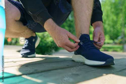 Tying sports shoes, man prepare for running in park