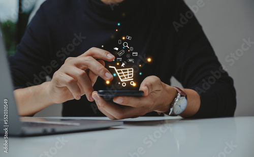 Obraz na plátne Young man using smartphone with shopping cart icon,  Online shopping and e-commerce concept