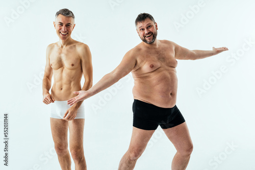 Two multiethnic men posing for a male edition body positive beauty set. Shirtless guys with different age  and body wearing boxers underwear
