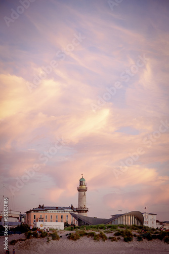 Romantic Sunset in Warnemünde: Teepott and Lighthouse Silhouettes against Dramatic Red Sky and Clouds over Baltic Sea Beach, Rostock Landmarks in Scenic Evening Coastal View