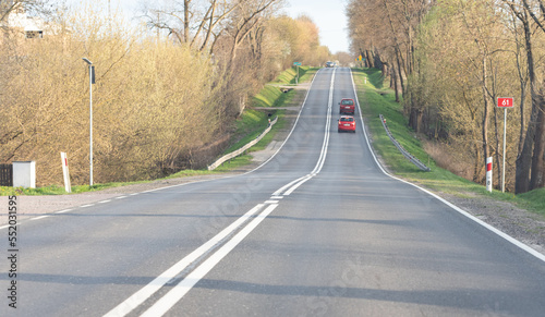 Pultusk, Poland - April 24, 2022: Car on the road in early spring. Greening grass and trees without leaves. photo