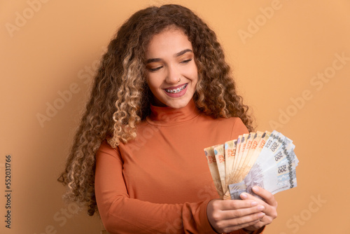Teen girl holding Brazilian currency real