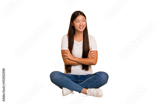 Young asian woman sitting on the floor cutout isolated smiling confident with crossed arms. © Asier