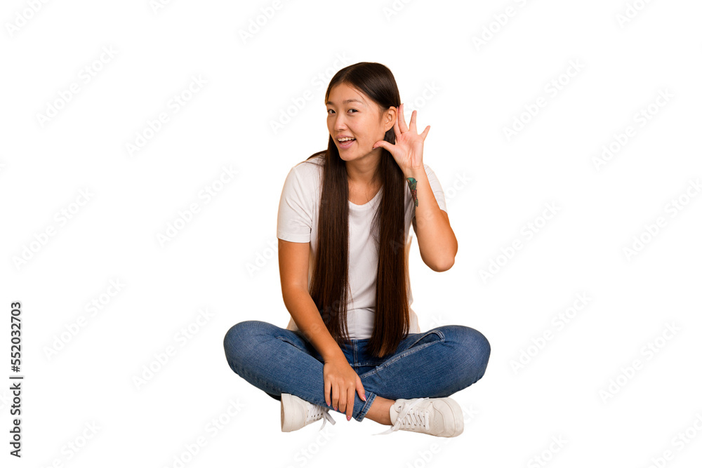 Young asian woman sitting on the floor cutout isolated trying to listening a gossip. Young asian woman sitting on the floor cutout isolated trying to listening a gossip.