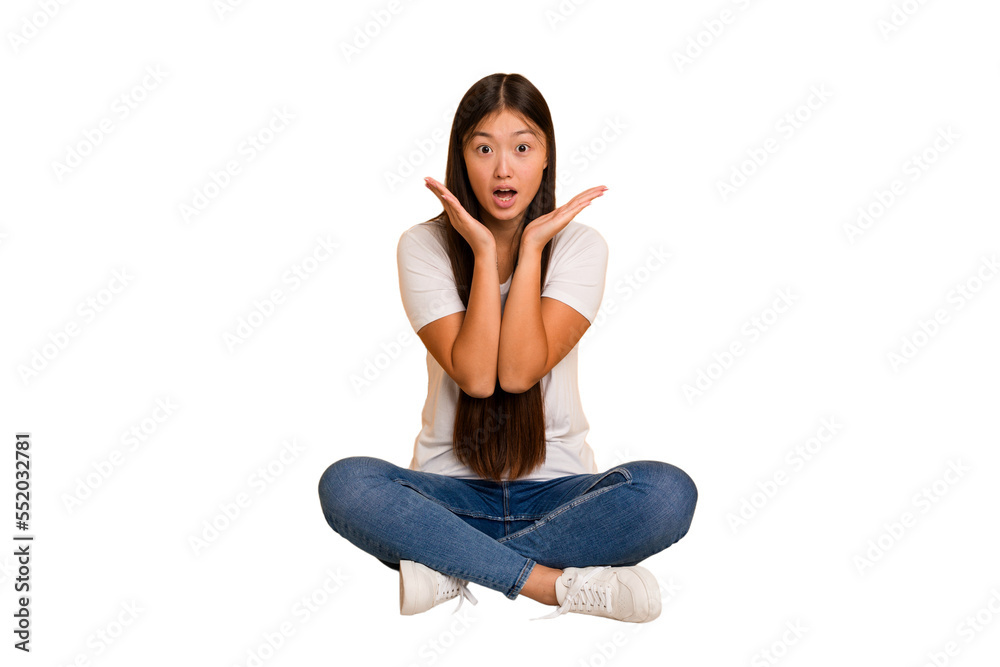 Young asian woman sitting on the floor cutout isolated surprised and shocked. Young asian woman sitting on the floor cutout isolated surprised and shocked.