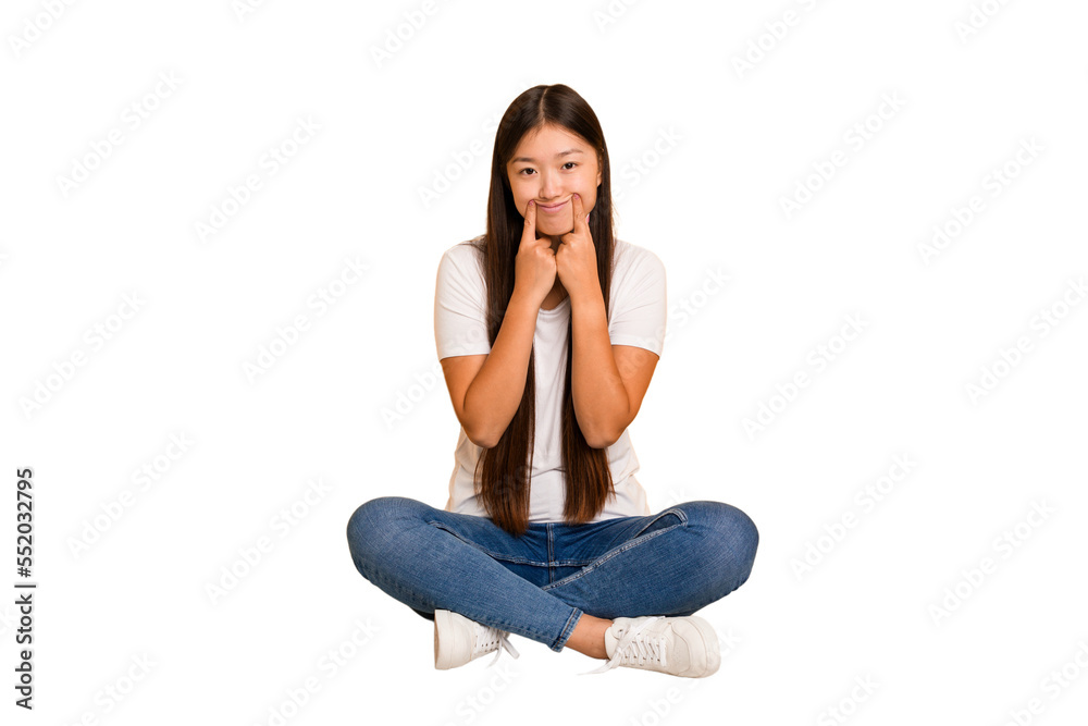 Young asian woman sitting on the floor cutout isolated doubting between two options. Young asian woman sitting on the floor cutout isolated doubting between two options.