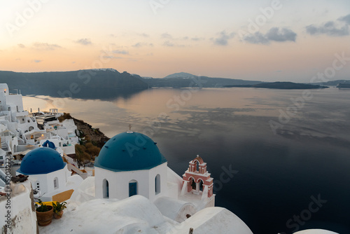 View at sunrise the famous blue domes and Aegean ocean in Oia, Santorini. The domes are from the churches of Agios Spiridonas (Saint Spyridon) and Anasteseos (the Church of the Resurrection)