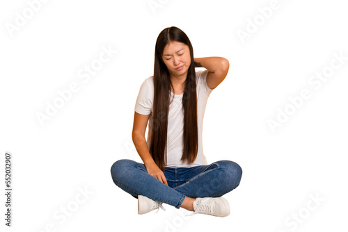 Young asian woman sitting on the floor cutout isolated having a neck pain due to stress, massaging and touching it with hand.