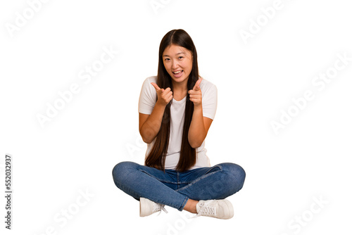 Young asian woman sitting on the floor cutout isolated pointing to front with fingers.