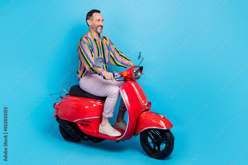 Photo of cheerful groomed charismatic glamour man sitting scooter riding city road look empty space isolated on blue color background