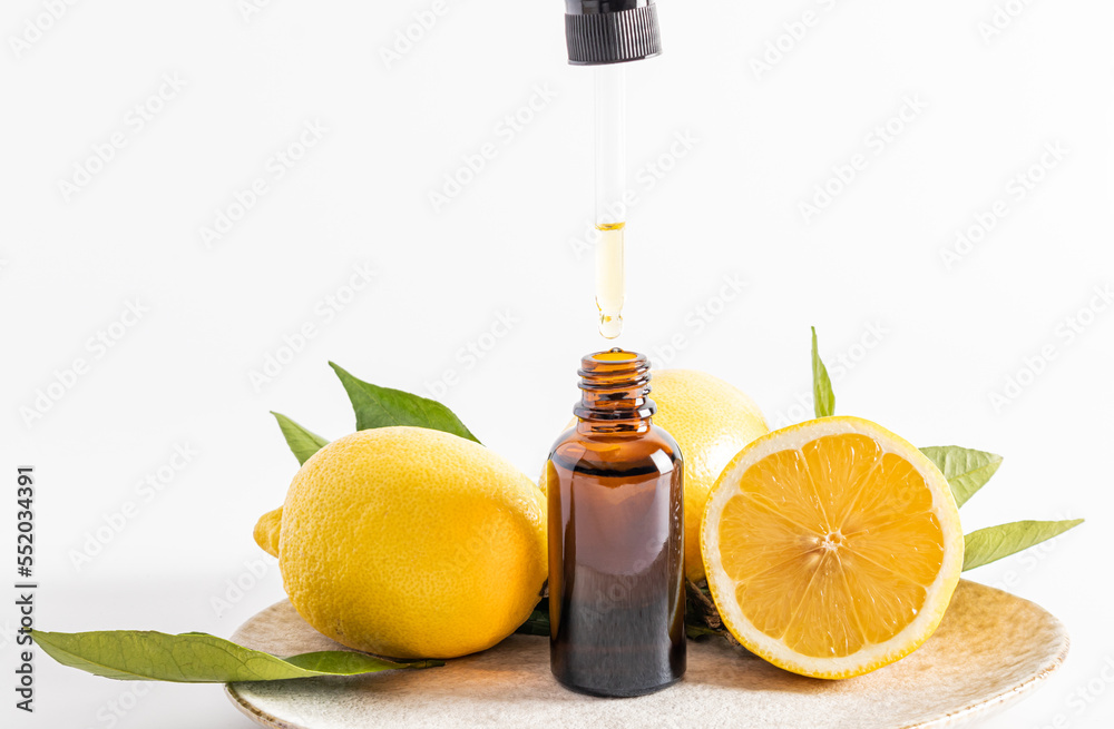 a natural organic facial skin care product based on lemon essential oil in a transparent bottle and pipette. white background. front view. a natural organic facial skin care product based on lemon essential oil in a transparent bottle and pipette. white background. front view.