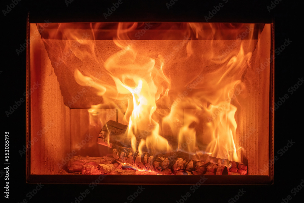 Fototapeta premium Fire flames and burning wood logs, energy stove fireplace close up,