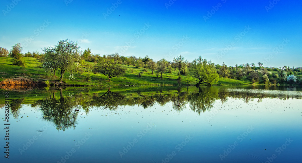 A pond in the countryside. The blue sky is reflected in the clear water.