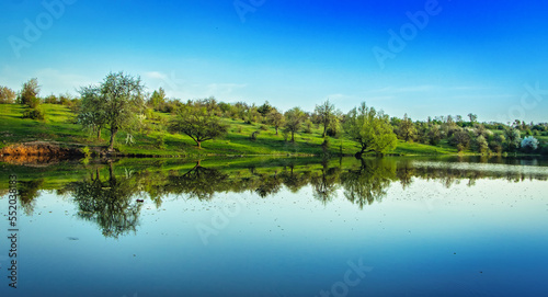 A pond in the countryside. The blue sky is reflected in the clear water.