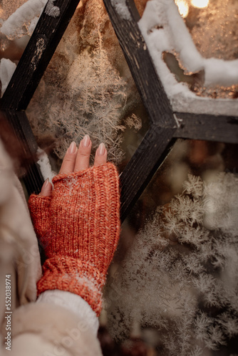 Fototapeta Naklejka Na Ścianę i Meble -  female hand in mittens on a background of frosty glass