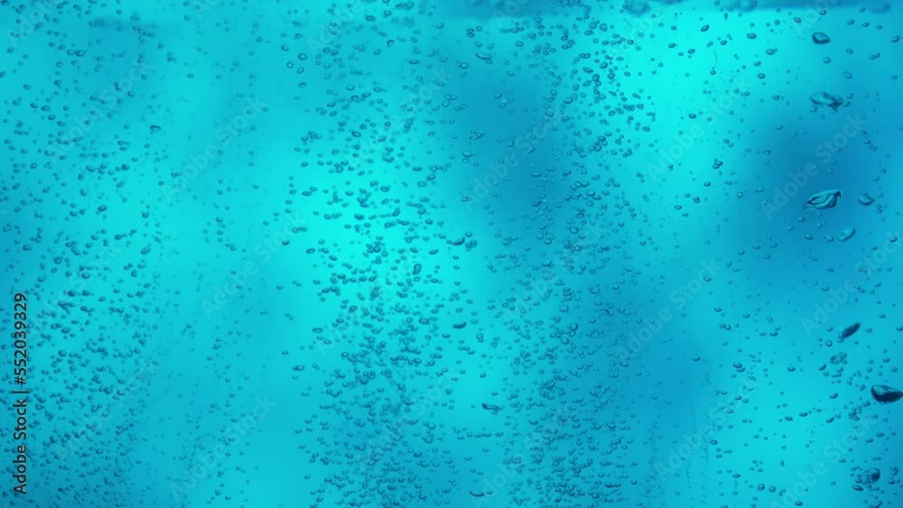 Lot of small shiny air bubbles rising from bottom to the surface on blue background. Close up of oxygen bubbles streaming upward underwater. Aeration or filtration of liquid. Slow motion. Lot of small shiny air bubbles rising from bottom to the surface on blue background. Close up of oxygen bubbles streaming upward underwater. Aeration or filtration of liquid. Slow motion.