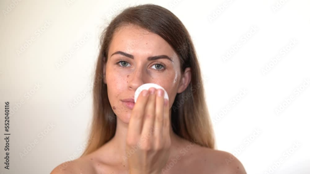 Girl removing makeup from her face with cotton pad Girl removing makeup from her face with cotton pad