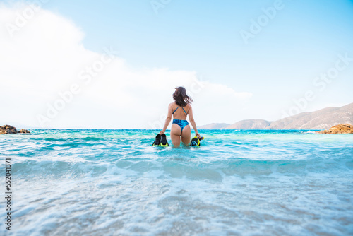 sexy woman in blue swimsuit going to the sea with with flippers and snorkeling mask