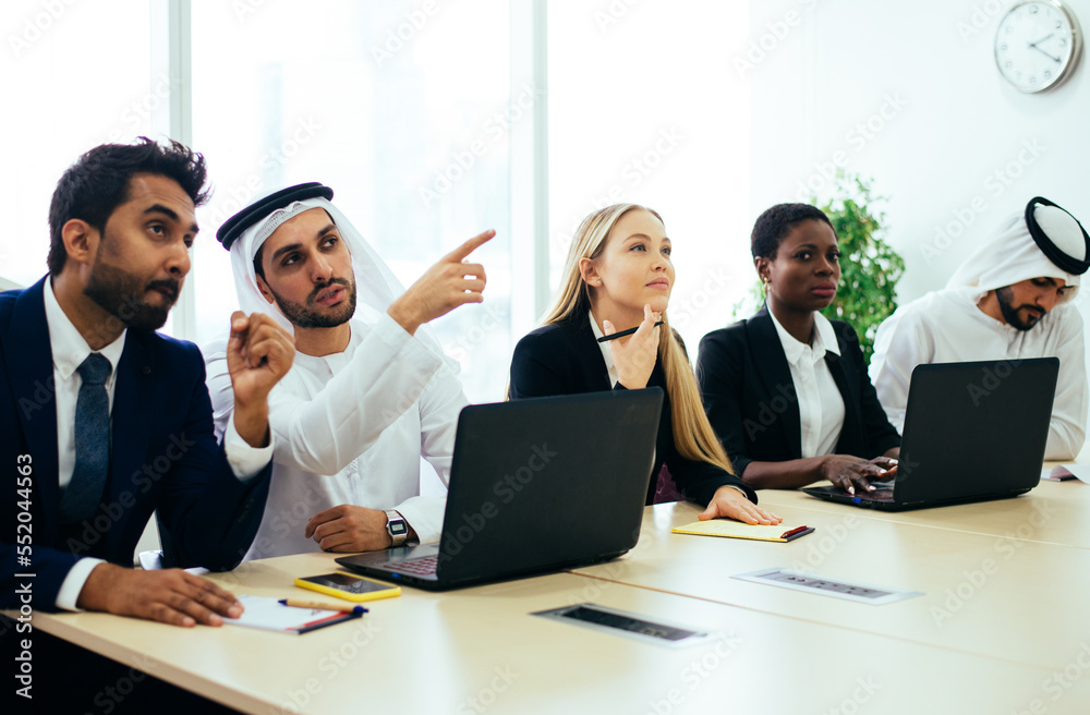 Multiethnic western and middle eastern business team working together in an office of Dubai. Sales people and employees at work on new projects Multiethnic western and middle eastern business team working together in an office of Dubai. Sales people and employees at work on new projects