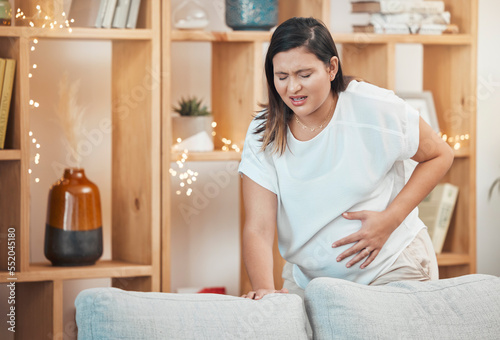 Pregnant woman, pain and cramps with hand on stomach for abdominal problem, discomfort or childbirth contractions for labour. Female with stress, stomachache or spasm causing miscarriage in pregnancy photo
