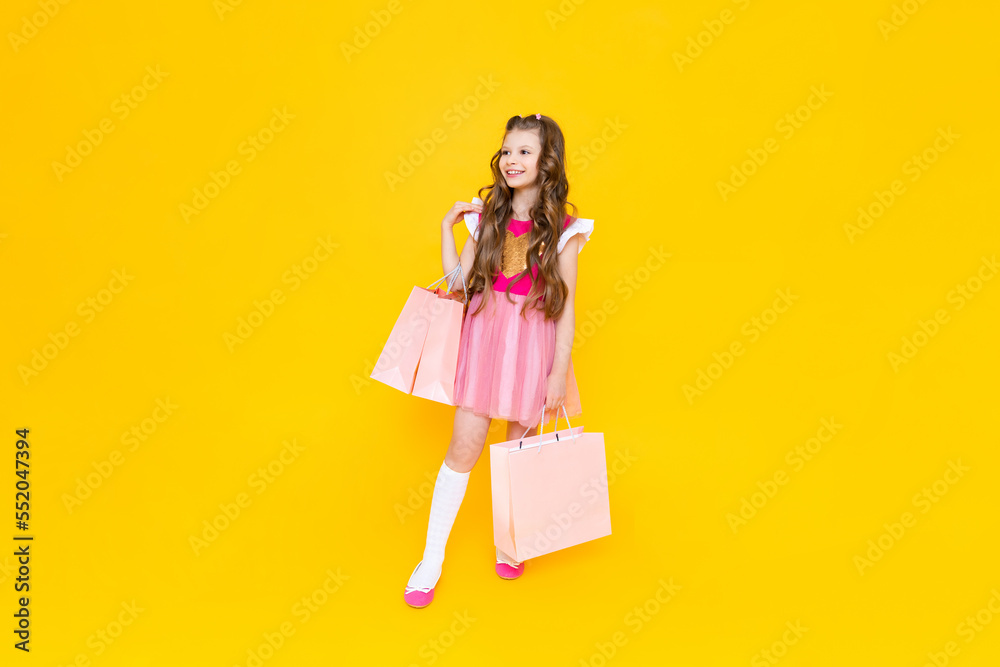 Spring discounts in children's stores on clothes and shoes, A little girl comes out of the store with big bags.