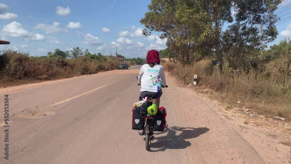 Back shot of women cycling in the jungle road in Laos. Back shot of women cycling in the jungle road in Laos.