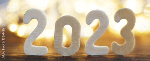 wooden number 2023 onchristmas beautifull shiny gold background. sparkle festive blurred bokeh photo