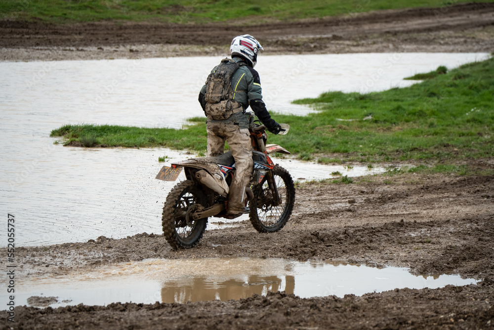 motorcyclist taking their off-road bike through muddy and very wet terrain, Wiltshire UK motorcyclist taking their off-road bike through muddy and very wet terrain, Wiltshire UK