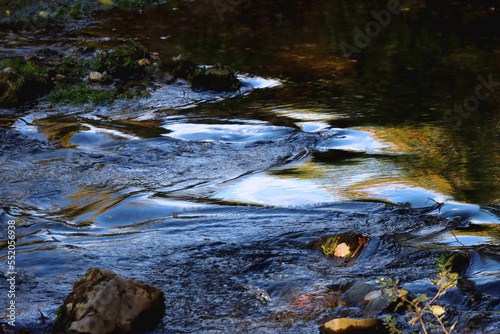 Fallen autumn leaves and small waterfall. Selective focus.