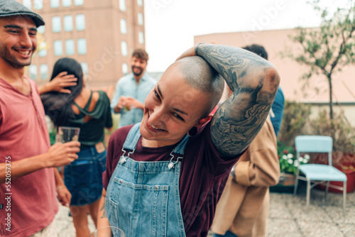 androgenic looking person with shaved head and tattoo smiling at party