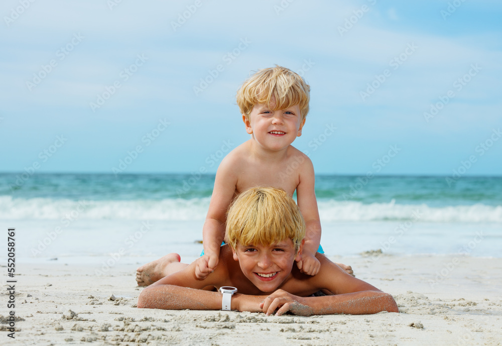 Two happy smiling boys lay together on sand ocean sea beach Two happy smiling boys lay together on sand ocean sea beach