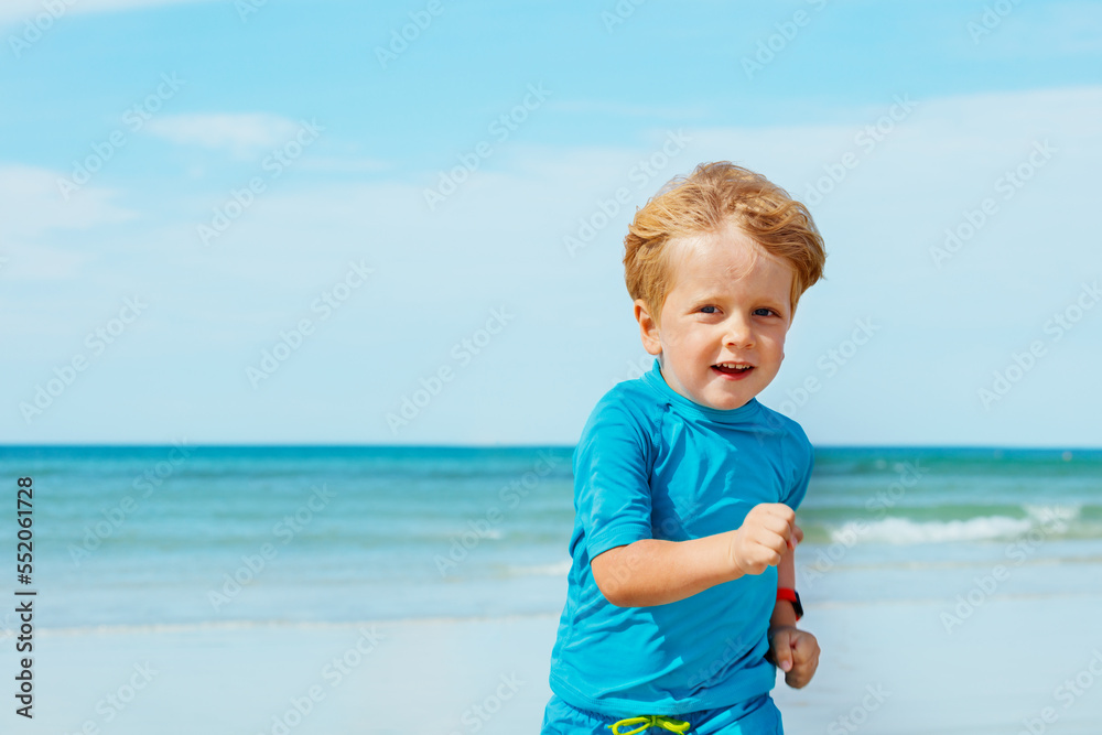 Close portrait of cute little boy run on sand beach over ocean Close portrait of cute little boy run on sand beach over ocean
