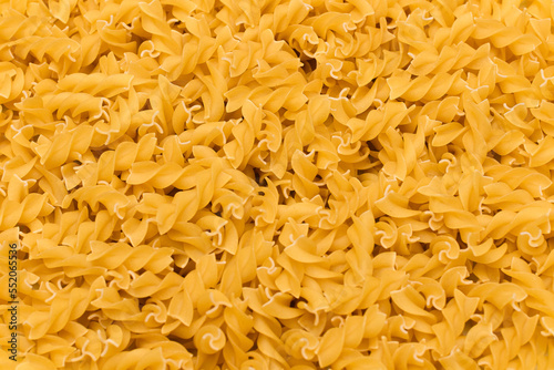 Uncooed Fusilli Pasta - Background. Texture of Bright Golden Dry Macaroni