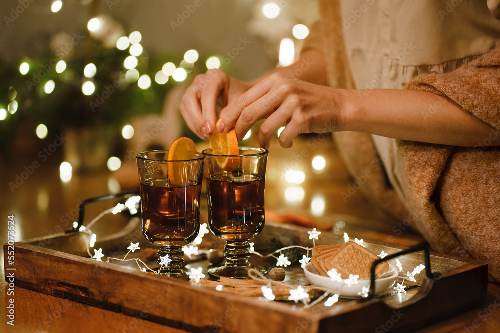 Female hands hold cup of tea next to cookies and Christmas tree on tray. Selective focus. Female hands hold cup of tea next to cookies and Christmas tree on tray. Selective focus.