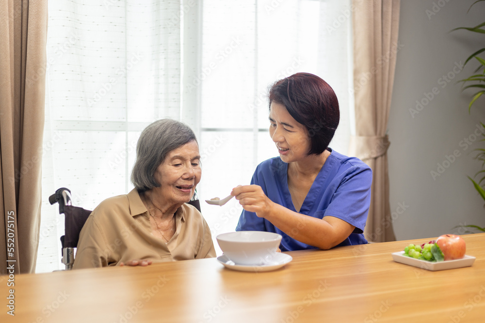 Caregiver feeding elderly asian woman with soup. Caregiver feeding elderly asian woman with soup.
