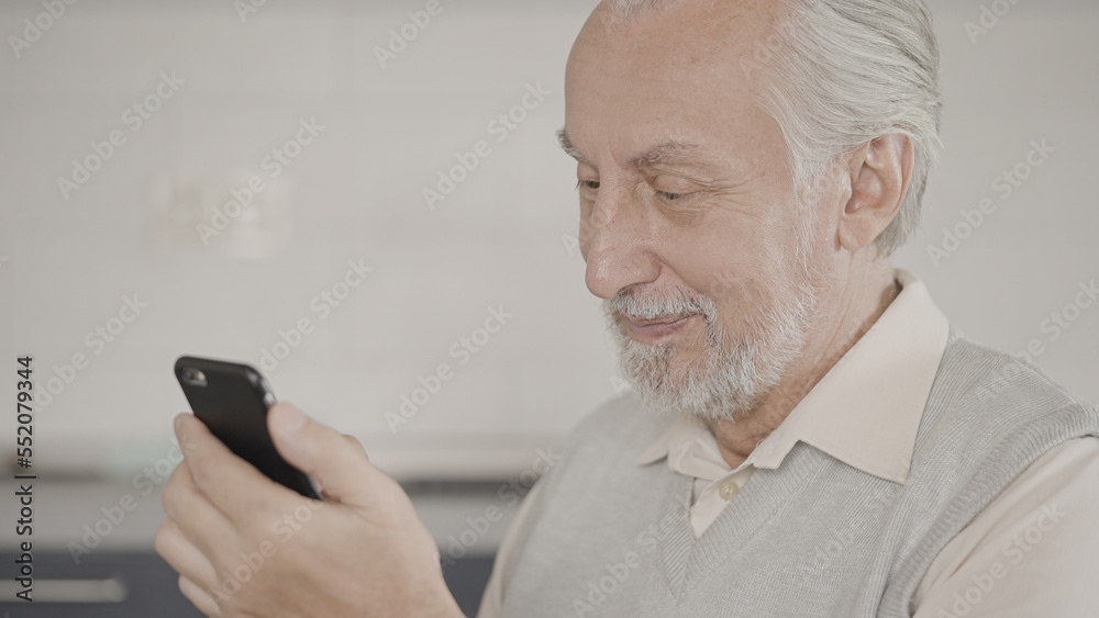 Happy senior man looking through family photos on phone and smiling, memories Happy senior man looking through family photos on phone and smiling, memories