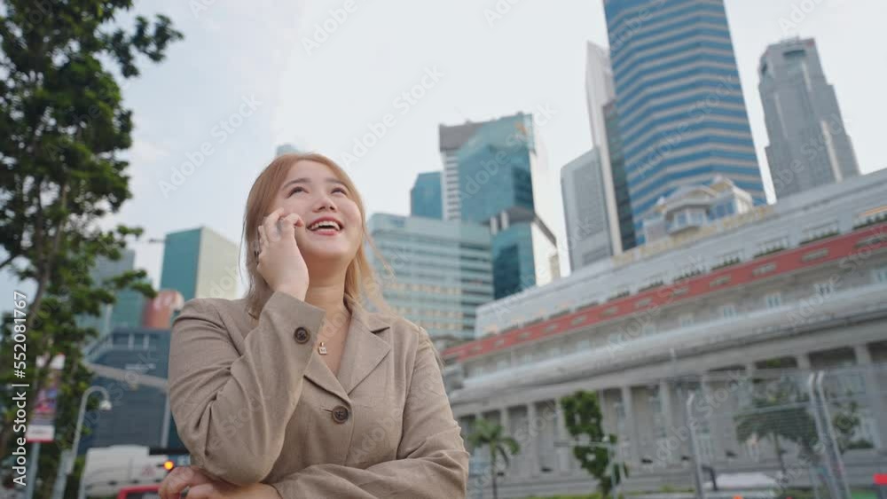 Happy and smilling face of asian businesswoman using smartphone talking with someone and standing at the city street Happy and smilling face of asian businesswoman using smartphone talking with someone and standing at the city street