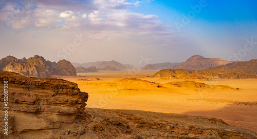 On a sunny october afternoon and after a downpour characteristic panorama of the wadi rum desert with the characteristic hills and residues of with clouds in the blue sky