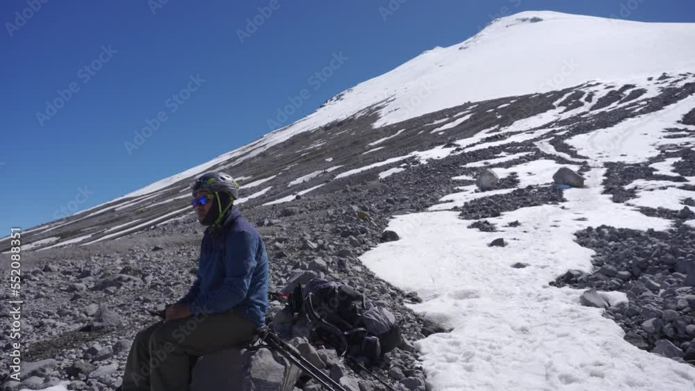 mountaineer sitting at the base of the glacier of pico de orizaba