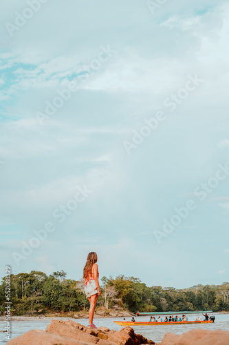 A girl watches a canoe on the Río Napo photo