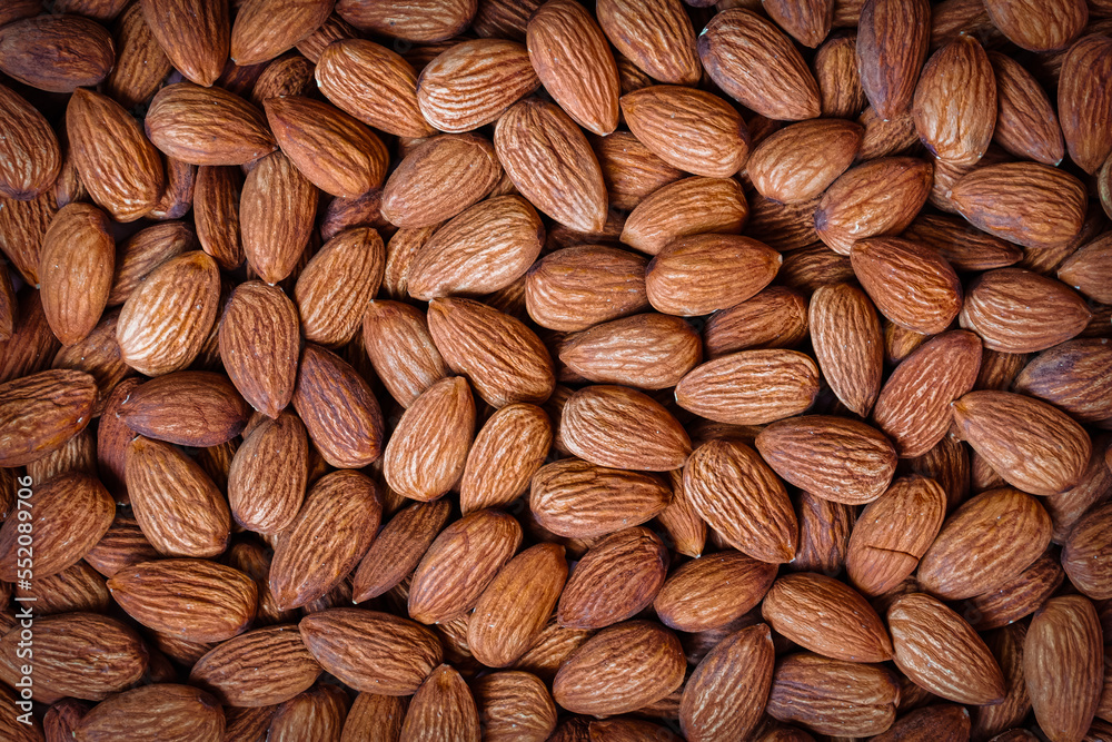 Almonds all over close-up. Brown fresh or roasted almond kernels top view, food background Almonds all over close-up. Brown fresh or roasted almond kernels top view, food background