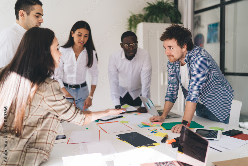 Cheerful multiethnic coworkers discussing project in modern workspace Cheerful multiethnic coworkers discussing project in modern workspace