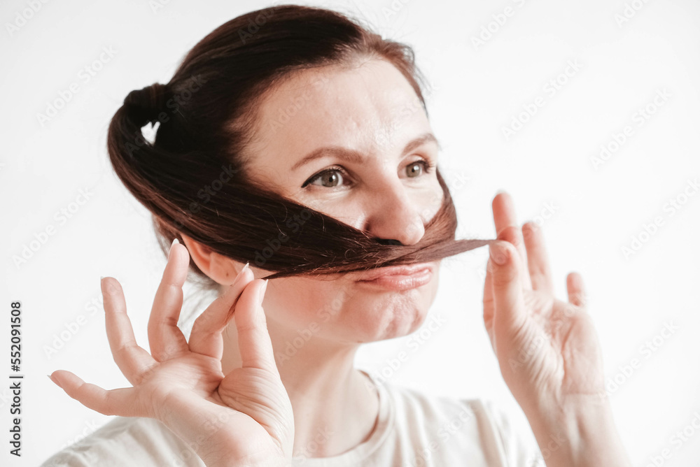Portrait of a beautiful woman who makes a mustache out of pigtails and a funny face on a white background Portrait of a beautiful woman who makes a mustache out of pigtails and a funny face on a white background