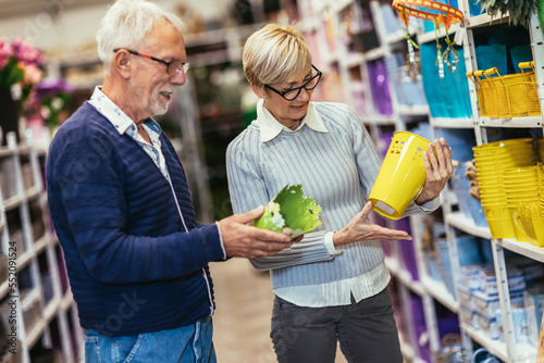 Senior couple are choosing pots at garden center.