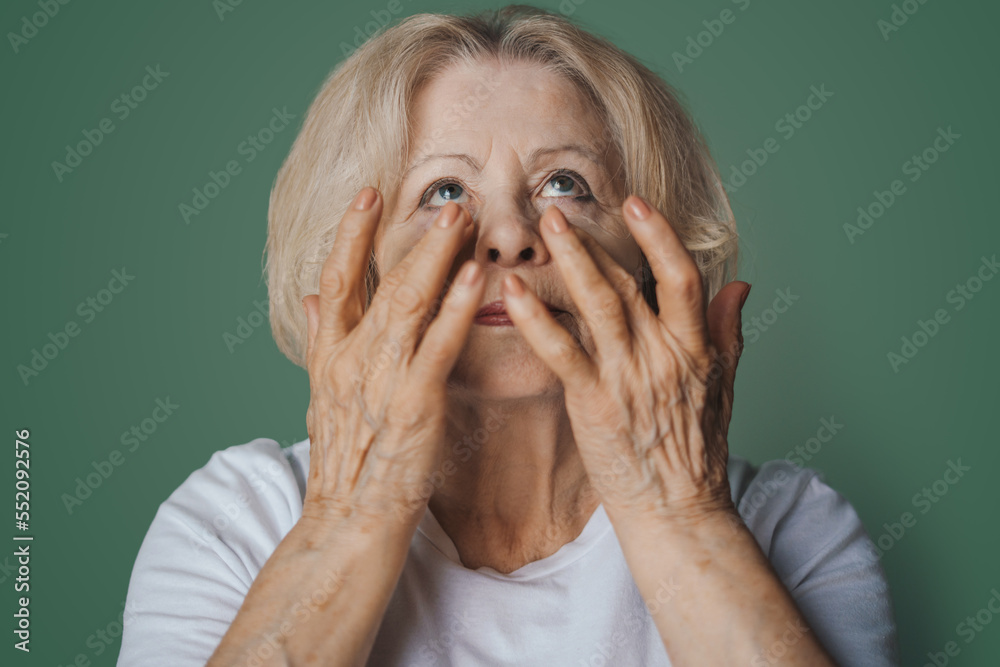 Portrait of pretty senior woman with hydrogel under-eye patches in the morning, showing an effect of perfect skin, isolated on green background. Anti aging Portrait of pretty senior woman with hydrogel under-eye patches in the morning, showing an effect of perfect skin, isolated on green background. Anti aging