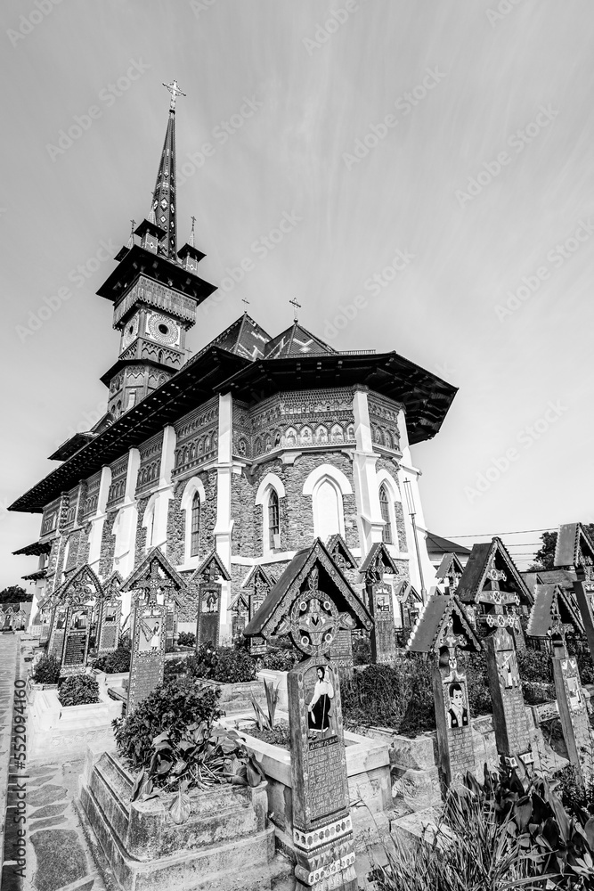 Sapanta, Maramures, Romania - August 2021: The orthodox church and traditional grave crosses in the Merry Cemetery; a UNESCO world heritage sire in black and white