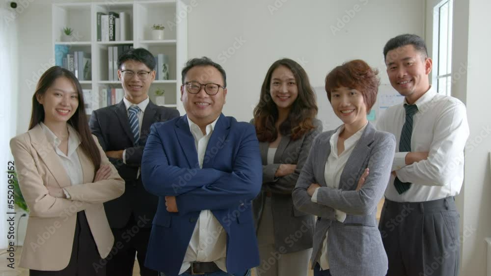 group of asian businesspeople with arms crossed in office..smiling young business professionals team standing among his colleagues. group of asian businesspeople with arms crossed in office..smiling young business professionals team standing among his colleagues.