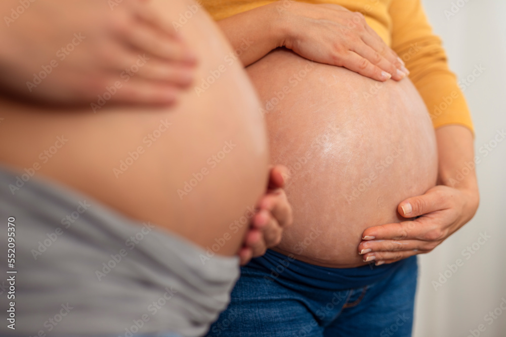 Two Pregnant Woman holding and stroking apply cream on big belly for beauty moisturizing skin at home Two Pregnant Woman holding and stroking apply cream on big belly for beauty moisturizing skin at home